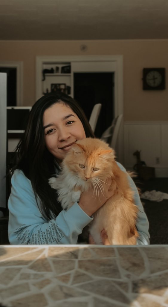 girl with dark hard holding orange long haired cat