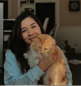 girl with dark hard holding orange long haired cat