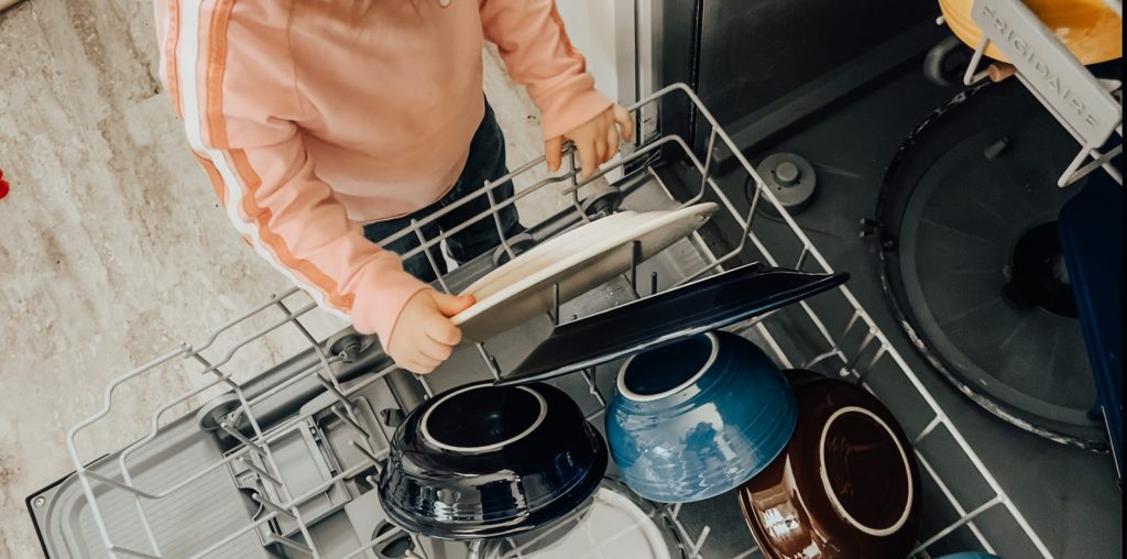Toddler helping new mom with the dishes