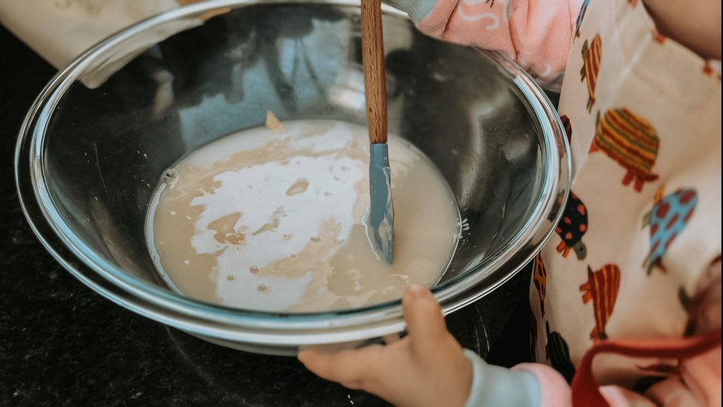 Little girl mixing sourdough bread 
starter
