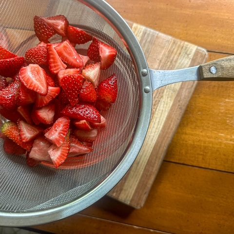 Close up of cut up strawberries in strainer
